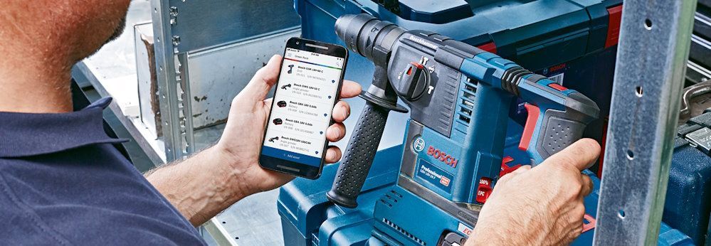 Person benutzt Smartphone und Akkubohrer